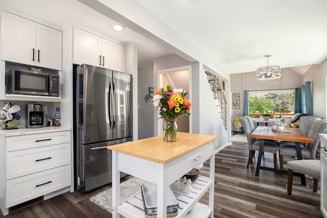 kitchen with appliances with stainless steel finishes, butcher block countertops, dark wood-style floors, white cabinets, and a chandelier