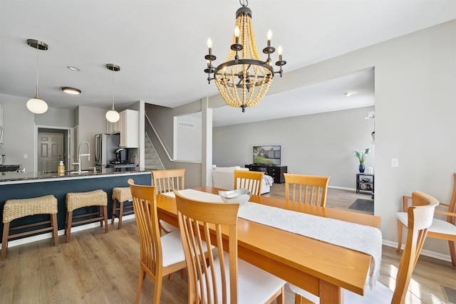 5639 Heathland Cir, Clarkston, MI 48346 - dining area featuring stairway, light wood-type flooring, a chandelier, and baseboards