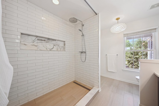 5639 Heathland Cir, Clarkston, MI 48346 - bathroom featuring a tile shower, toilet, vanity, baseboards, and wood finished floors