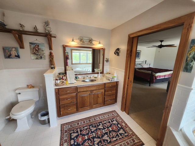 5005 S Brye Rd, Ludington, MI 49431 - ensuite bathroom with wainscoting, tile patterned flooring, toilet, vanity, and a ceiling fan