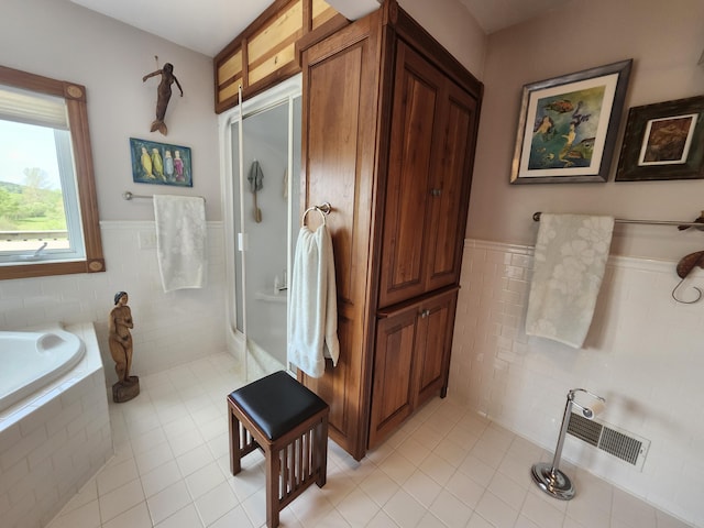 5005 S Brye Rd, Ludington, MI 49431 - bathroom featuring tile patterned floors, tile walls, walk in shower, tiled bath, and a wainscoted wall