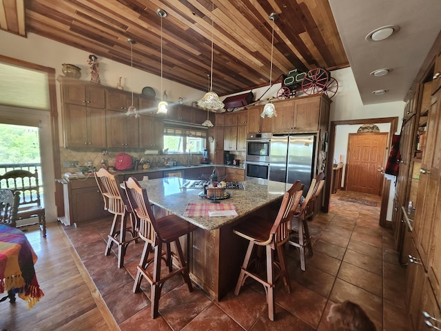 5005 S Brye Rd, Ludington, MI 49431 - kitchen with stainless steel appliances, vaulted ceiling, a center island, backsplash, and light stone counters