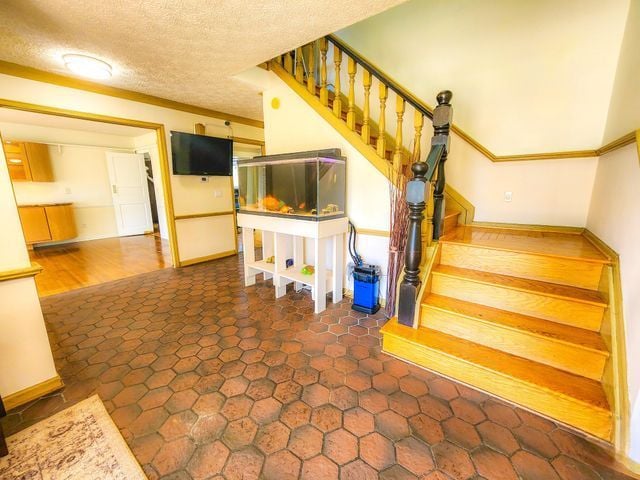 5130 Lake Bluff Rd, West Bloomfield, MI 48323 - staircase featuring baseboards, a textured ceiling, and ornamental molding