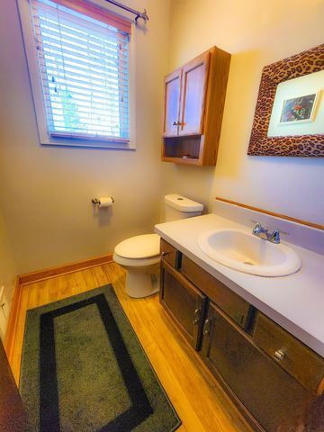 5130 Lake Bluff Rd, West Bloomfield, MI 48323 - half bathroom featuring wood finished floors, toilet, vanity, and baseboards
