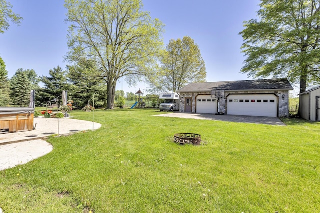 8595 Rives Junction Rd, Rives Junction, MI 49277 - view of green lawn with a playground, a hot tub, a detached garage, and a fire pit