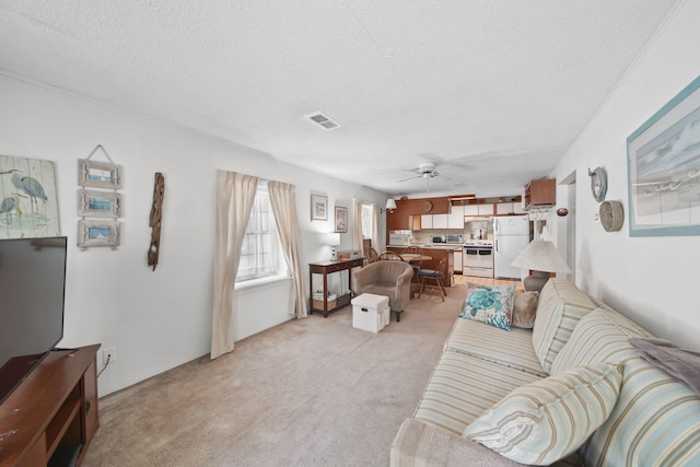 living area featuring a ceiling fan, light carpet, and a textured ceiling