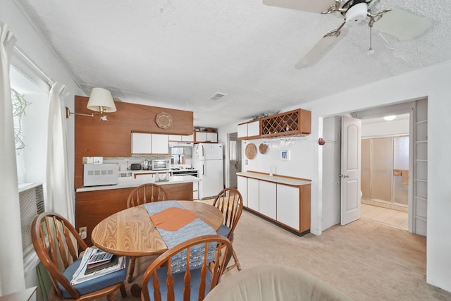 dining space with light colored carpet, a textured ceiling, and ceiling fan