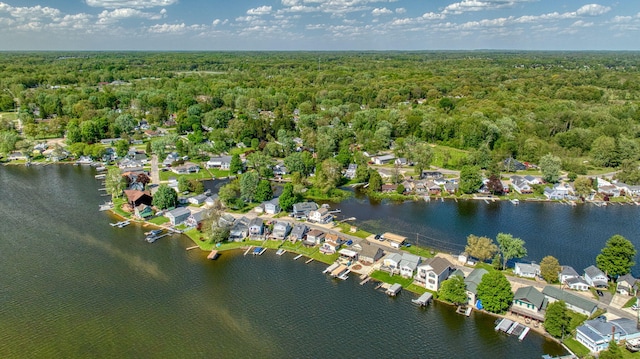 view of property location with a heavily wooded area, nearby suburban area, and a large body of water