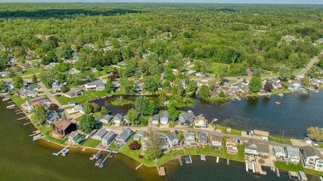 aerial view of property's location featuring a forest, a large body of water, and nearby suburban area