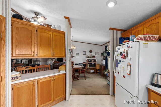1633 Lavender Dr, Hastings, MI 49058 - kitchen featuring freestanding refrigerator, a textured ceiling, light countertops, brown cabinetry, and light colored carpet