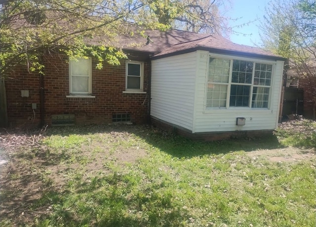 view of home's exterior with a lawn and brick siding