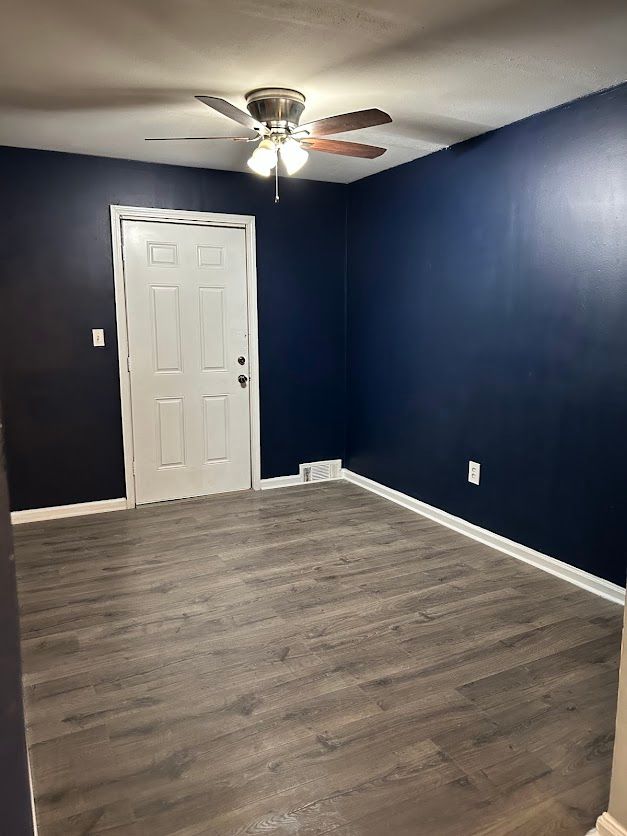 unfurnished room with ceiling fan, wood finished floors, and baseboards