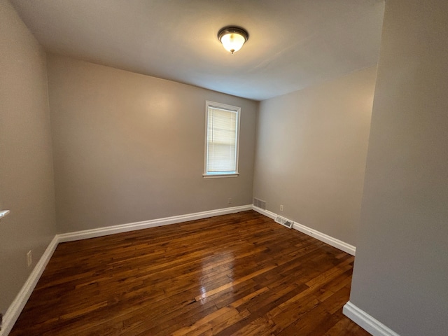 unfurnished room with dark wood finished floors and baseboards
