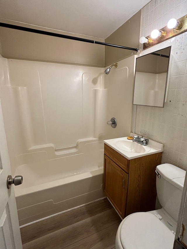 18989 Washtenaw St, Harper Woods, MI 48225 - bathroom with tile walls, toilet, wood finished floors, vanity, and tub / shower combination
