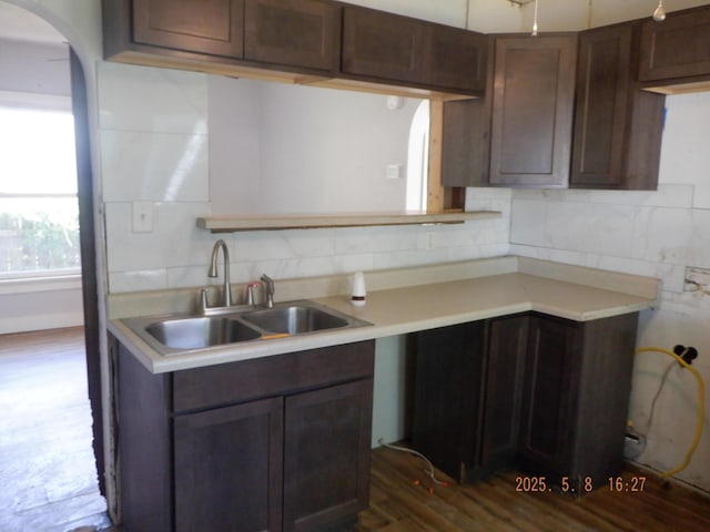 824 Gayle Ave, Kalamazoo, MI 49048 - kitchen featuring a sink, arched walkways, dark wood-type flooring, and decorative backsplash