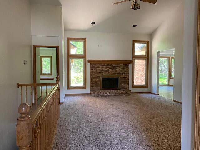 28379 Emerald Ct, Chesterfield, MI 48047 - unfurnished living room featuring healthy amount of natural light, carpet floors, ceiling fan, a fireplace, and lofted ceiling