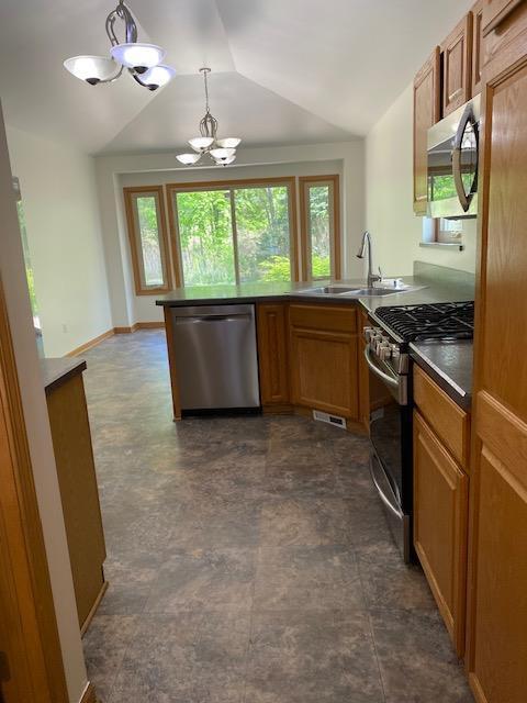 28379 Emerald Ct, Chesterfield, MI 48047 - kitchen with appliances with stainless steel finishes, a peninsula, lofted ceiling, a sink, and brown cabinetry
