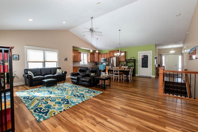 12250 Aleigha Dr NW, Grand Rapids, MI 49534 - living room featuring ceiling fan, vaulted ceiling, wood finished floors, a chandelier, and baseboards