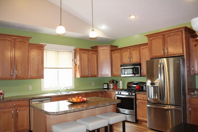 12250 Aleigha Dr NW, Grand Rapids, MI 49534 - kitchen featuring stainless steel appliances, lofted ceiling, a sink, a breakfast bar, and a kitchen island