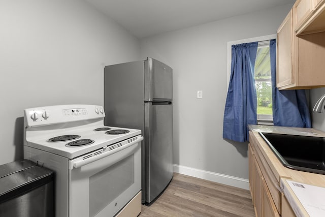 12550 Devoe St, Southgate, MI 48195 - kitchen with electric stove, freestanding refrigerator, light brown cabinetry, light wood-type flooring, and a sink