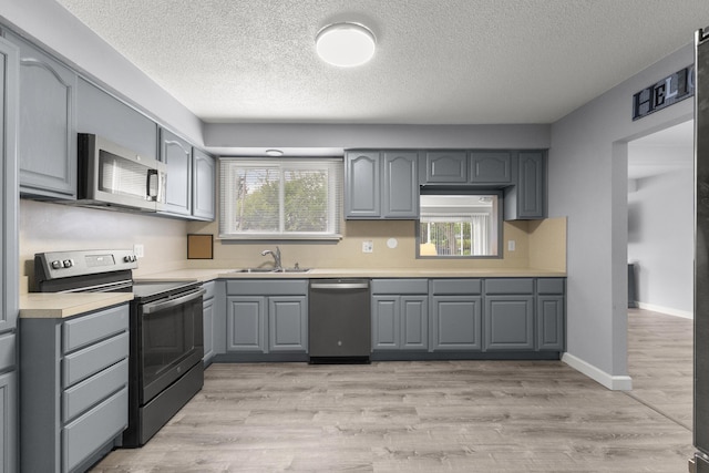12550 Devoe St, Southgate, MI 48195 - kitchen with stainless steel appliances, gray cabinetry, a sink, a textured ceiling, and light countertops