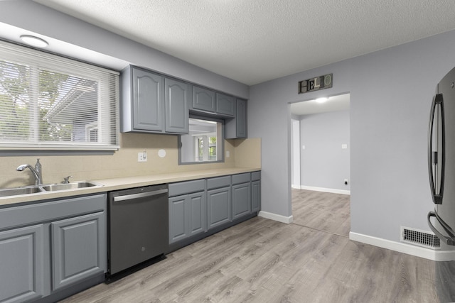 12550 Devoe St, Southgate, MI 48195 - kitchen with dishwasher, a sink, gray cabinetry, light wood-style flooring, and light countertops