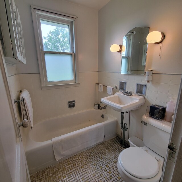 1614 Mooreville Rd, Milan, MI 48160 - bathroom with tile walls, toilet, a tub, a wainscoted wall, and a sink