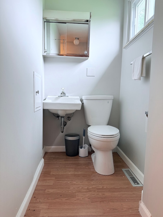 1666 Kile Rd, Metamora, MI 48455 - half bathroom featuring baseboards, toilet, wood finished floors, and a sink