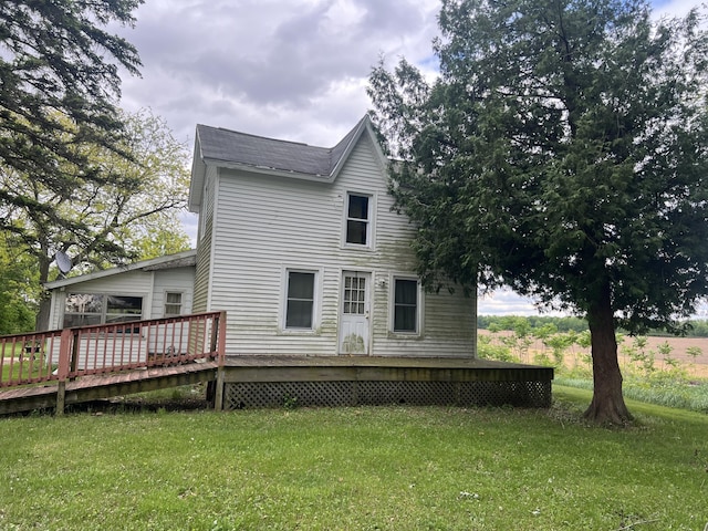back of property with a wooden deck and a yard