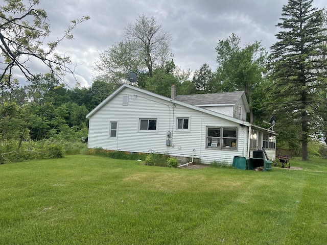 back of property with a yard and a shingled roof