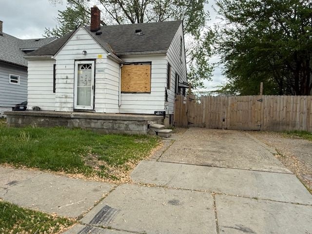 bungalow-style home featuring a chimney, fence, roof with shingles, and a gate