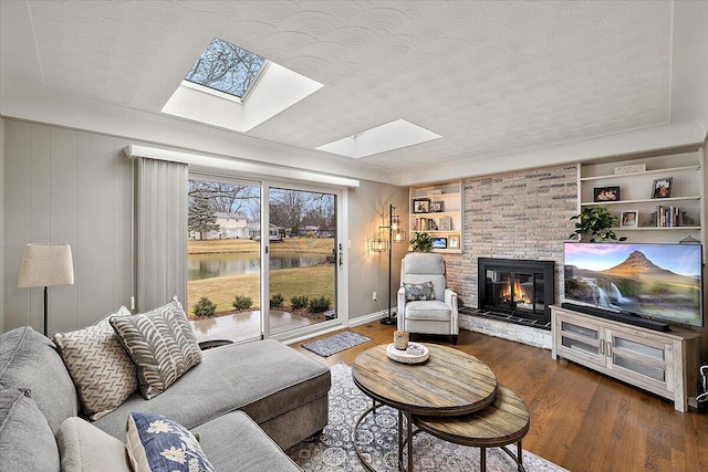 53383 Starlite Dr, Michigan, MI 48316 - living area featuring a skylight, wood finished floors, a brick fireplace, a textured ceiling, and built in features