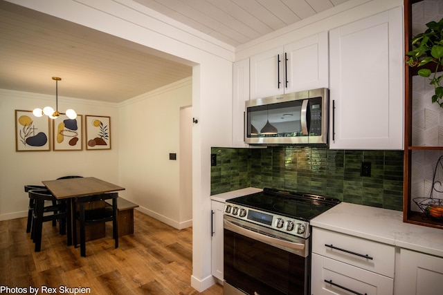 2490 S Parsons Ave, Fremont, MI 49412 - kitchen with stainless steel appliances, crown molding, a chandelier, white cabinets, and decorative backsplash