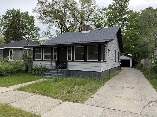 bungalow-style home with a chimney, a shingled roof, an outbuilding, and a garage