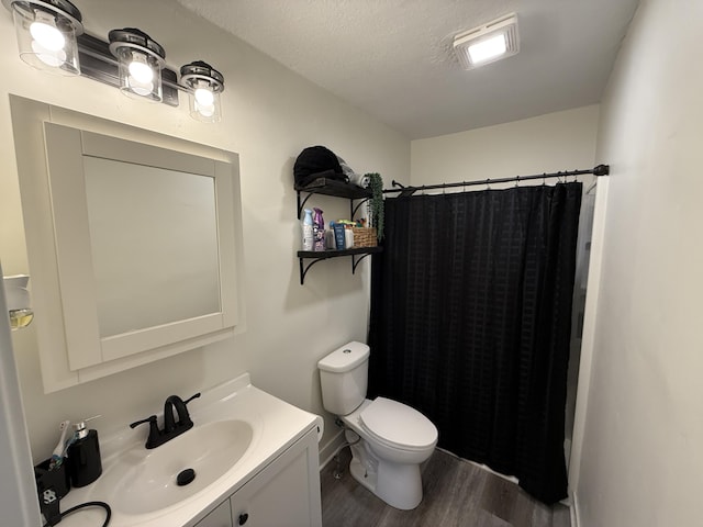 bathroom featuring wood finished floors, toilet, vanity, a shower with curtain, and a textured ceiling