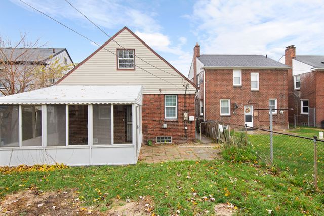 18711 Indiana St, Detroit, MI 48221 - rear view of property featuring a sunroom, brick siding, and a chimney