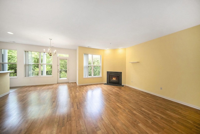 3197 Asher Rd, Ann Arbor, MI 48104 - unfurnished living room featuring a chandelier, wood finished floors, a warm lit fireplace, and baseboards