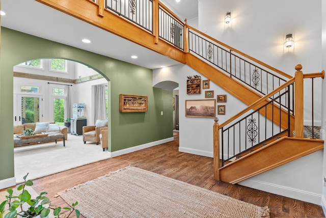 4263 Windmill Farms, Milford, MI 48380 - staircase featuring arched walkways, wood finished floors, a towering ceiling, baseboards, and recessed lighting
