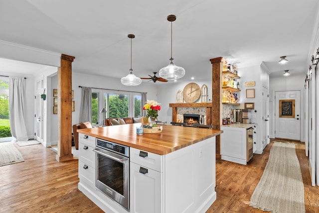 4263 Windmill Farms, Milford, MI 48380 - kitchen with wooden counters, stainless steel oven, ornamental molding, a stone fireplace, and plenty of natural light
