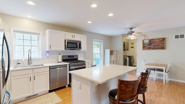 1670 Edwin Dr, Brighton, MI 48114 - kitchen with appliances with stainless steel finishes, washing machine and dryer, a sink, a breakfast bar area, and backsplash