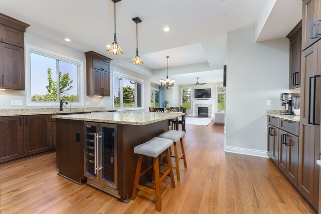 10408 Stoney Point Dr, South Lyon, MI 48178 - kitchen with wine cooler, a kitchen island, dark brown cabinetry, light wood-style flooring, and recessed lighting