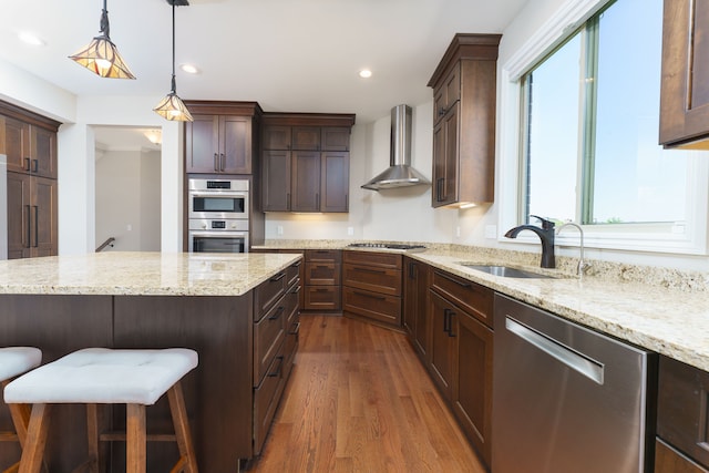 10408 Stoney Point Dr, South Lyon, MI 48178 - kitchen with stainless steel appliances, wall chimney exhaust hood, a sink, dark wood-type flooring, and a breakfast bar area
