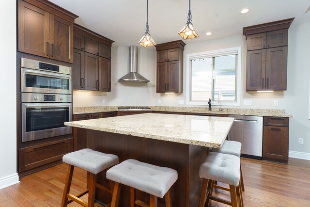 10408 Stoney Point Dr, South Lyon, MI 48178 - kitchen featuring appliances with stainless steel finishes, wall chimney exhaust hood, light wood-type flooring, a kitchen island, and recessed lighting