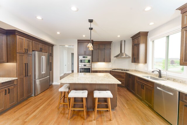 10408 Stoney Point Dr, South Lyon, MI 48178 - kitchen featuring appliances with stainless steel finishes, wall chimney range hood, a sink, a kitchen island, and a kitchen breakfast bar