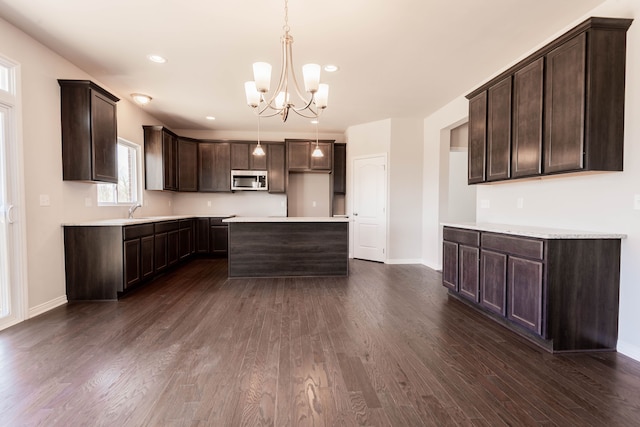 53209 Woodland Mdws, Clinton Township, MI 48047 - kitchen with stainless steel microwave, dark brown cabinets, a chandelier, dark wood finished floors, and baseboards