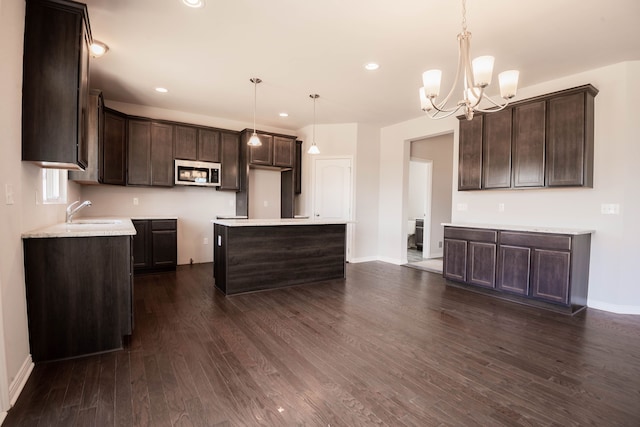 53209 Woodland Mdws, Clinton Township, MI 48047 - kitchen with stainless steel microwave, dark brown cabinetry, a sink, a chandelier, and recessed lighting