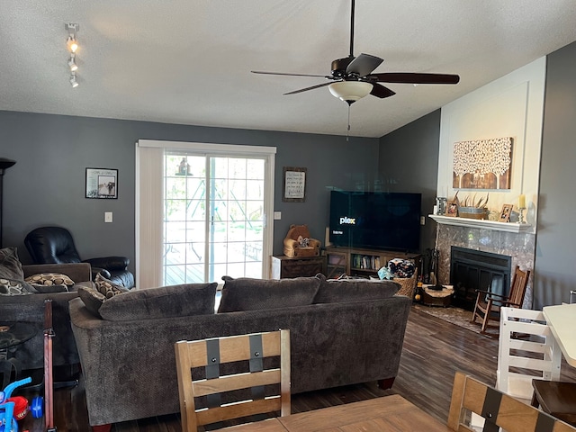 living room with a ceiling fan, a tiled fireplace, and wood finished floors