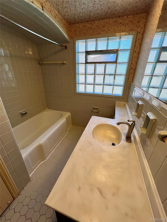 2332 Nolen Dr, Flint, MI 48504 - bathroom featuring tile patterned floors, tile walls, tub / shower combination, wallpapered walls, and vanity