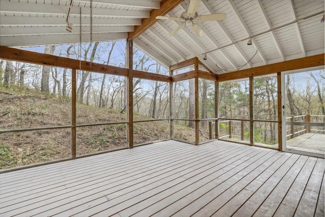 unfurnished sunroom featuring a ceiling fan, a deck, plenty of natural light, and high vaulted ceiling