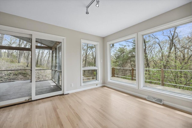 unfurnished sunroom with wood finished floors, baseboards, and track lighting